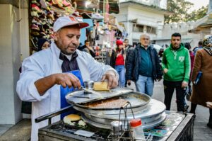 A street vendor prepares food in the bustling market of Tangier, Morocco.